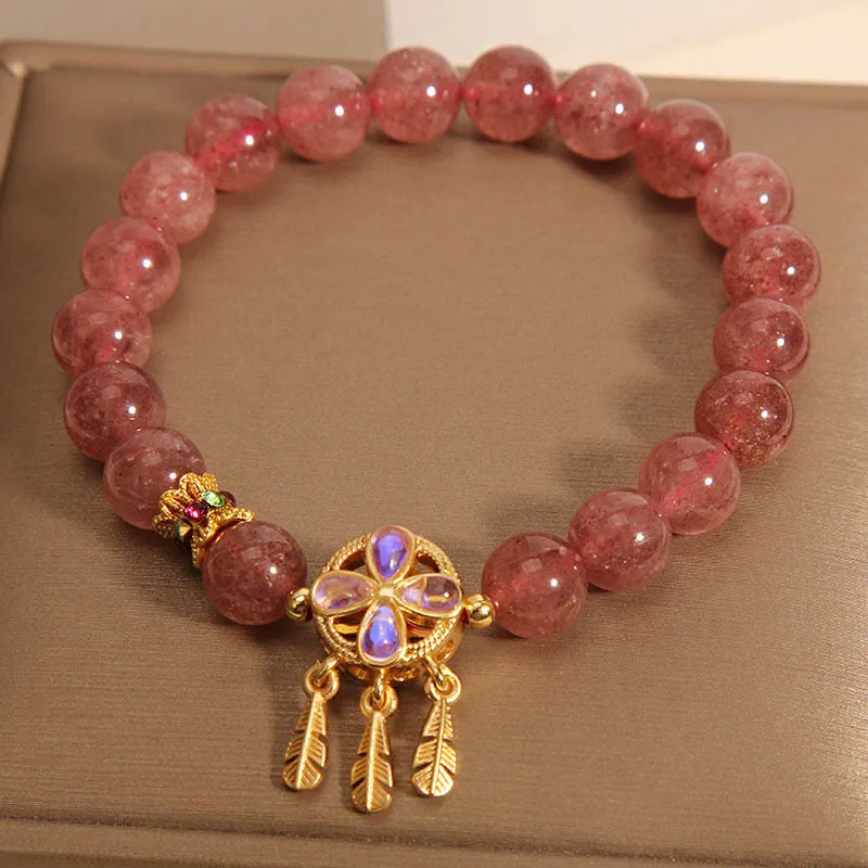 Women's strawberry quartz dream catcher ball pendant bracelet on wrist.