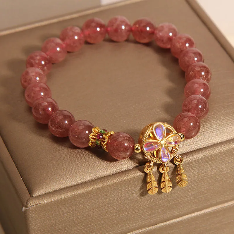Women's strawberry quartz dream catcher ball pendant bracelet on wrist.