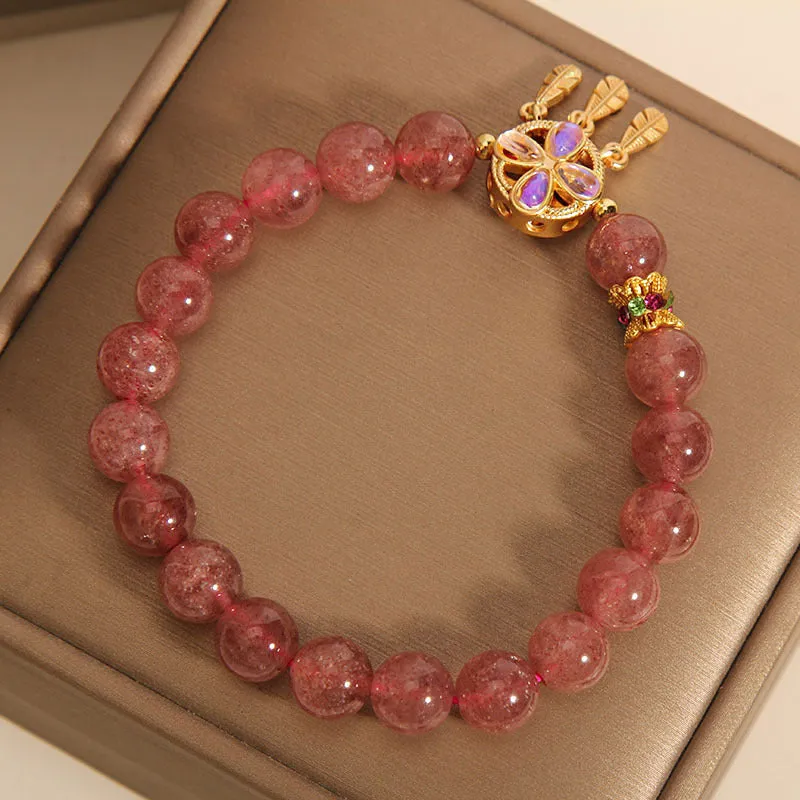 Women's strawberry quartz dream catcher ball pendant bracelet on wrist.