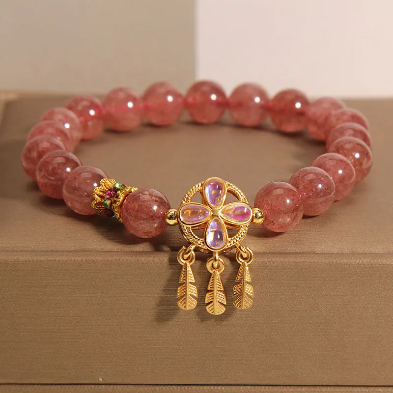 Women's strawberry quartz dream catcher ball pendant bracelet on wrist.