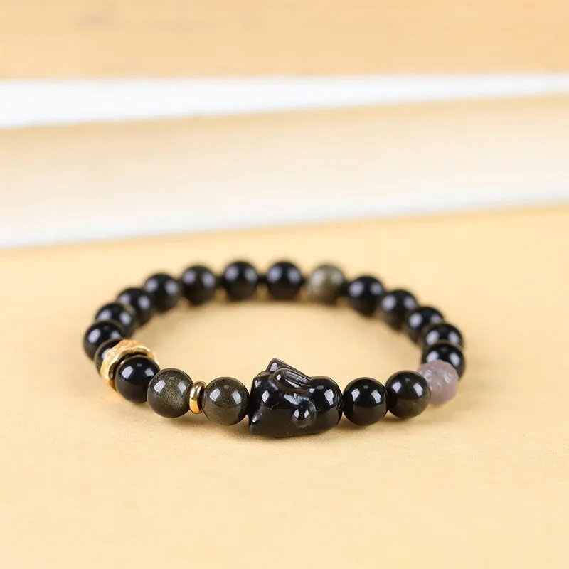 Handmade grey obsidian lying rabbit bracelet with brass and silver details on a wrist, shown in 8mm and 10mm size options.