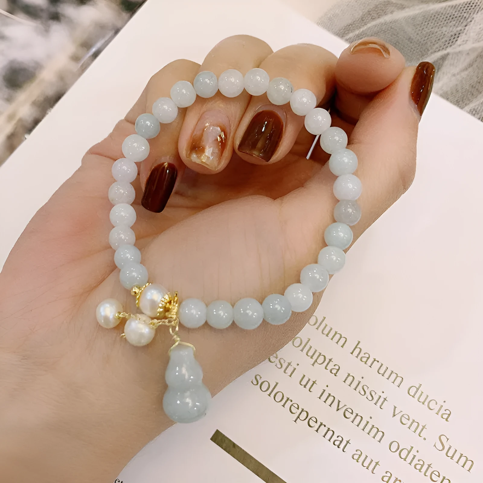 Chinese style jade bracelet with gourd charm and pearl accents on wrist