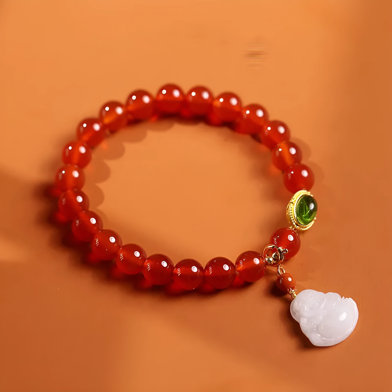 Chinese style geometric women's bracelet with red agate beads and a gold jade Maitreya Buddha pendant.