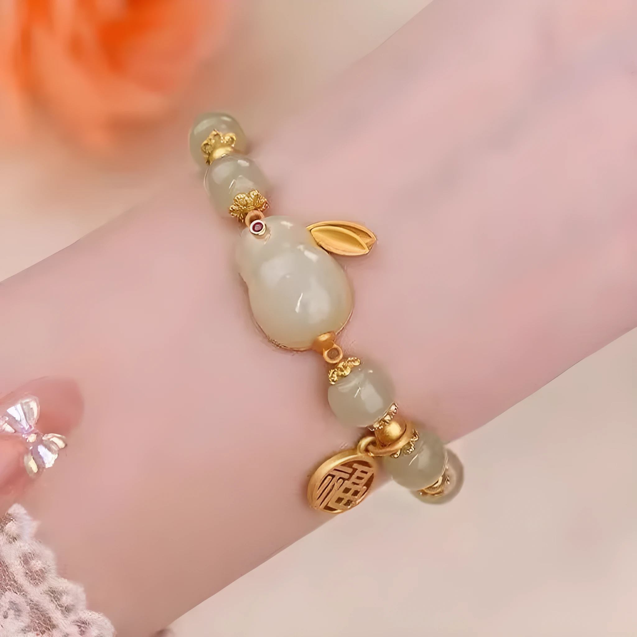 Green jade hare bracelet on wrist showing fu character and lily design details.