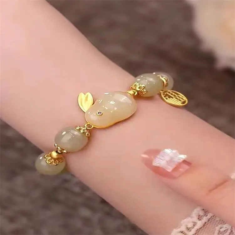 Green jade hare bracelet on wrist showing fu character and lily design details.