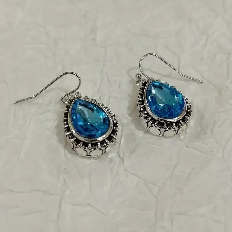 Pair of retro drop-shaped silver alloy earrings with blue gem inlay on white background