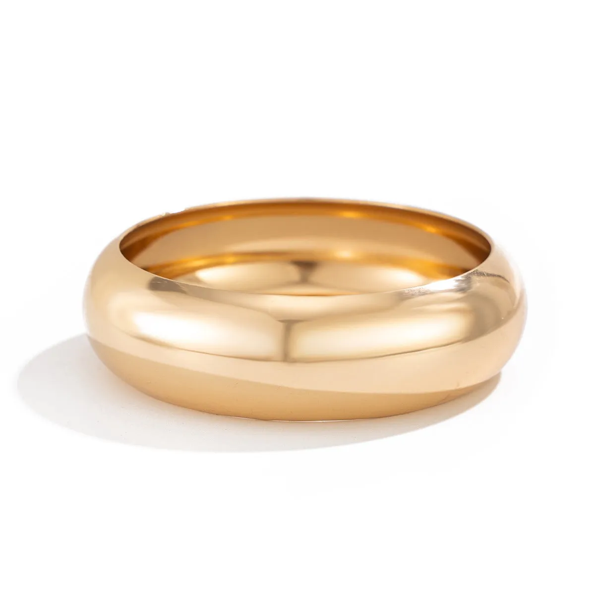 Exaggerated wide round glossy metal bracelet in gold tone on plain background