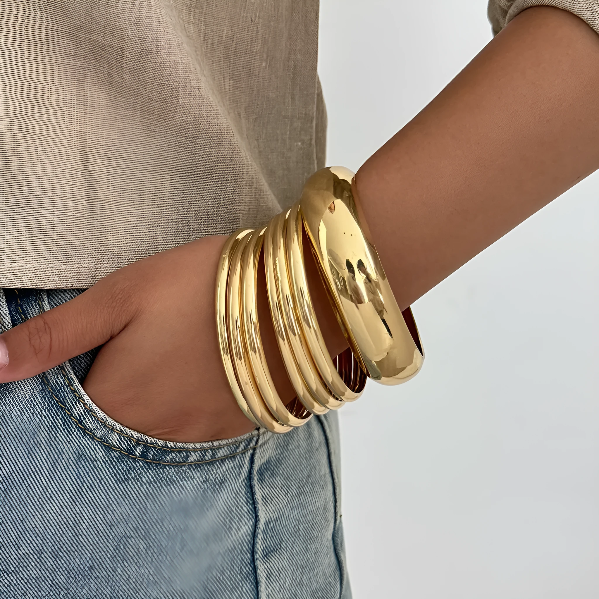 Exaggerated wide round glossy metal bracelet in gold tone on plain background