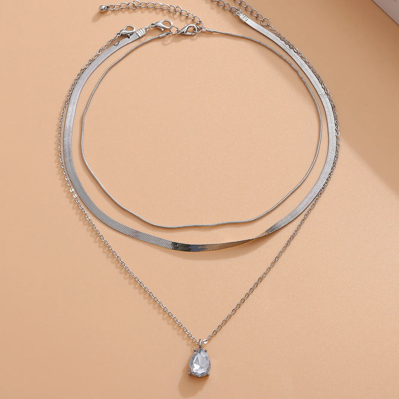 Gold and silver water drop shape alloy pendant necklace with electroplated finish on white background