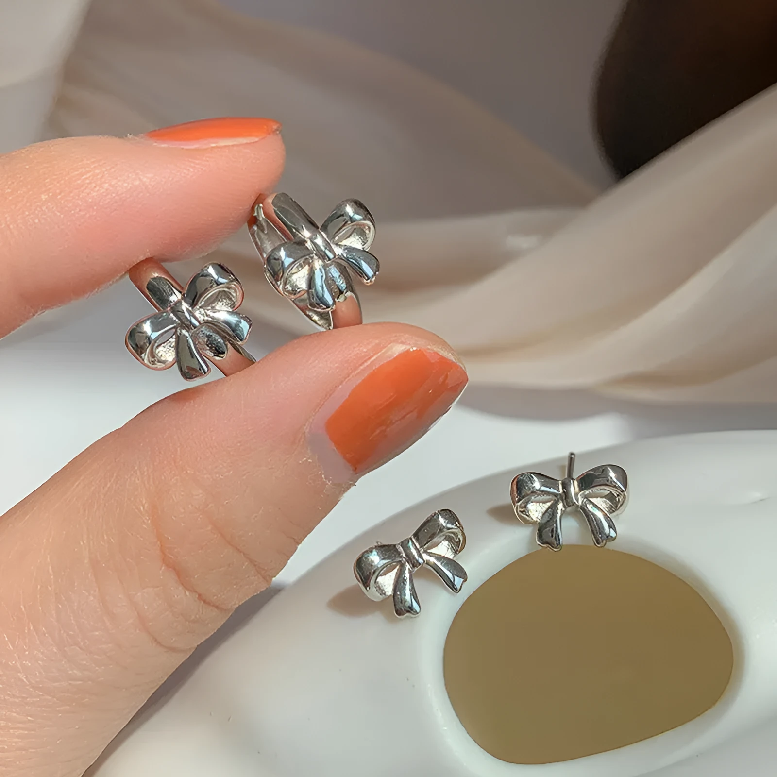 Pair of 925 sterling silver bow earrings with electroplated silver finish on white background