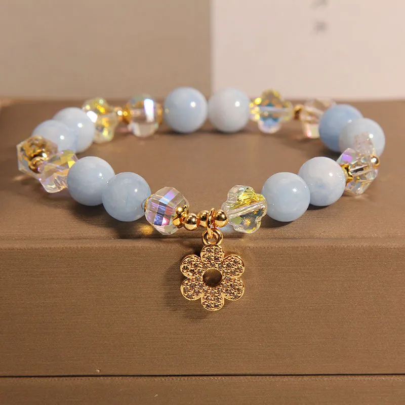 Women's aquamarine crystal bracelet with a four-leaf clover charm and pearl accent on wrist.