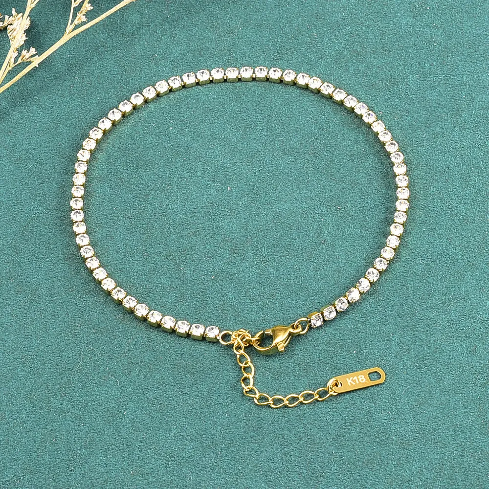Gold titanium steel anklet with small fruit-shaped pendant and adjustable tail chain on bare ankle