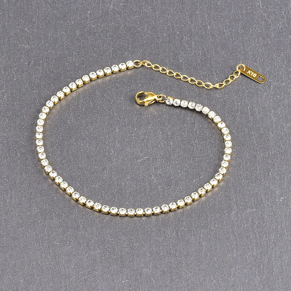 Gold titanium steel anklet with small fruit-shaped pendant and adjustable tail chain on bare ankle