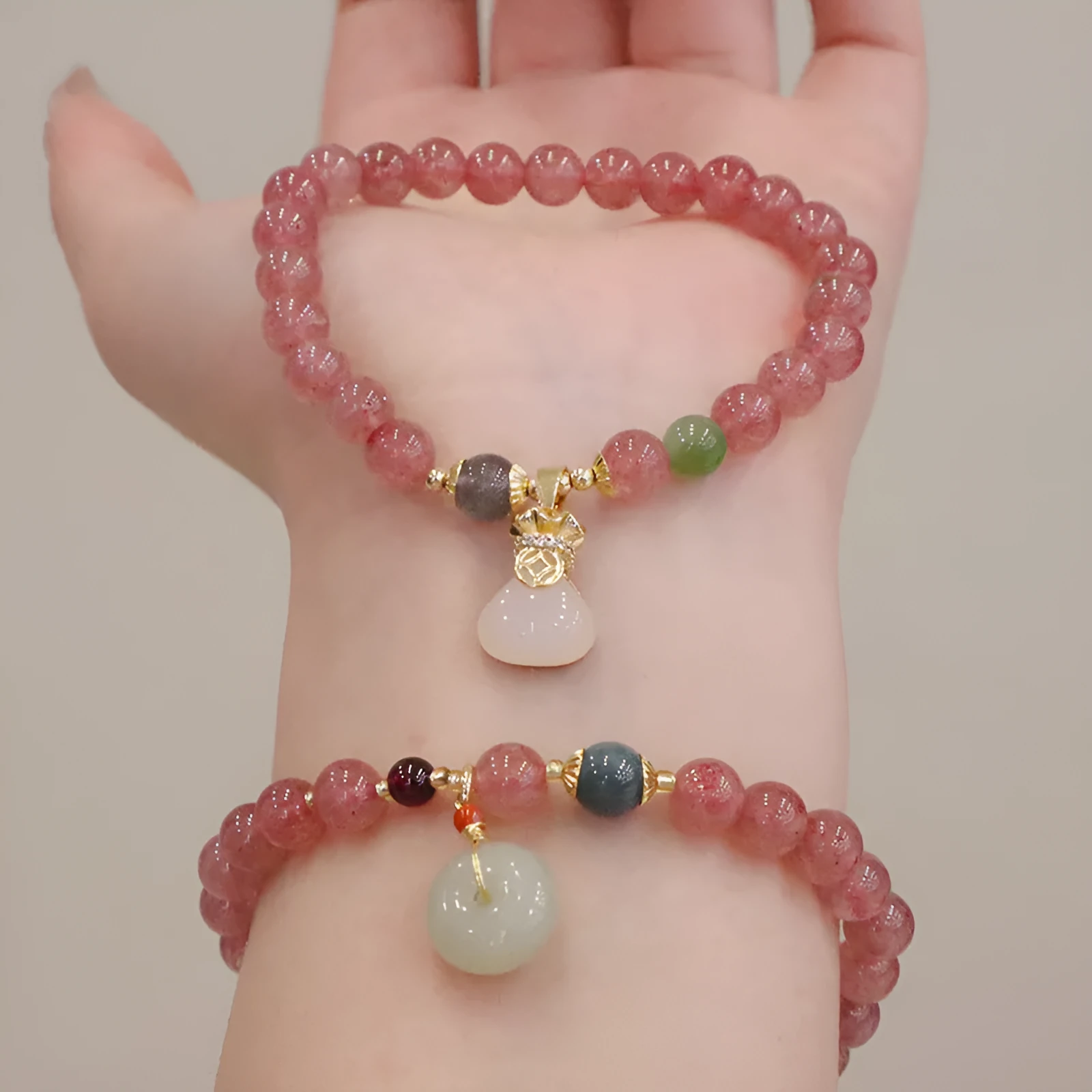 Women's strawberry quartz bracelet with geometric stones, purse charm and lucky bagg charm on wrist