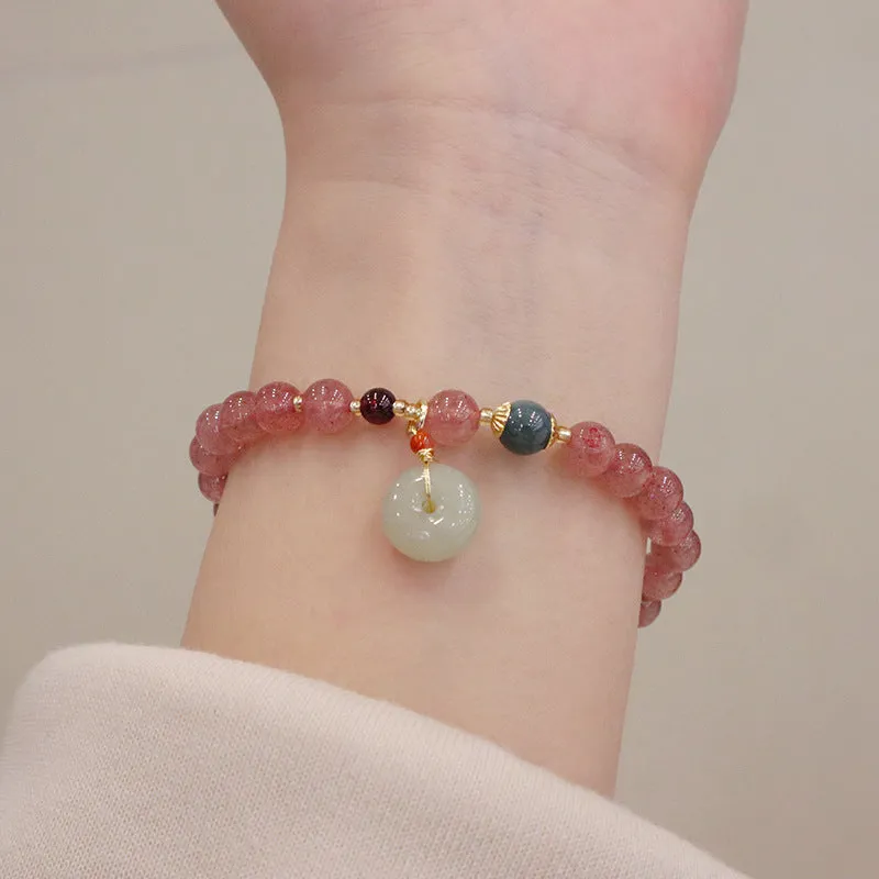 Women's strawberry quartz bracelet with geometric stones, purse charm and lucky bagg charm on wrist