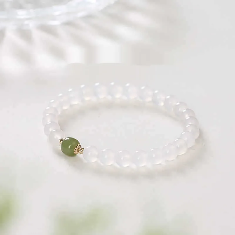 Handmade natural white agate and Hetian jade crystal bracelet with cinnabar inlay on a wrist.