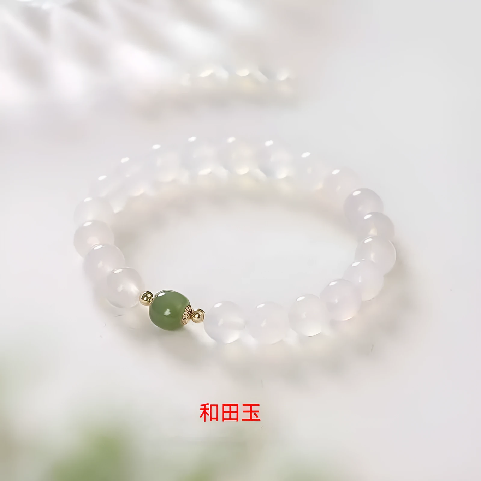Handmade natural white agate and Hetian jade crystal bracelet with cinnabar inlay on a wrist.