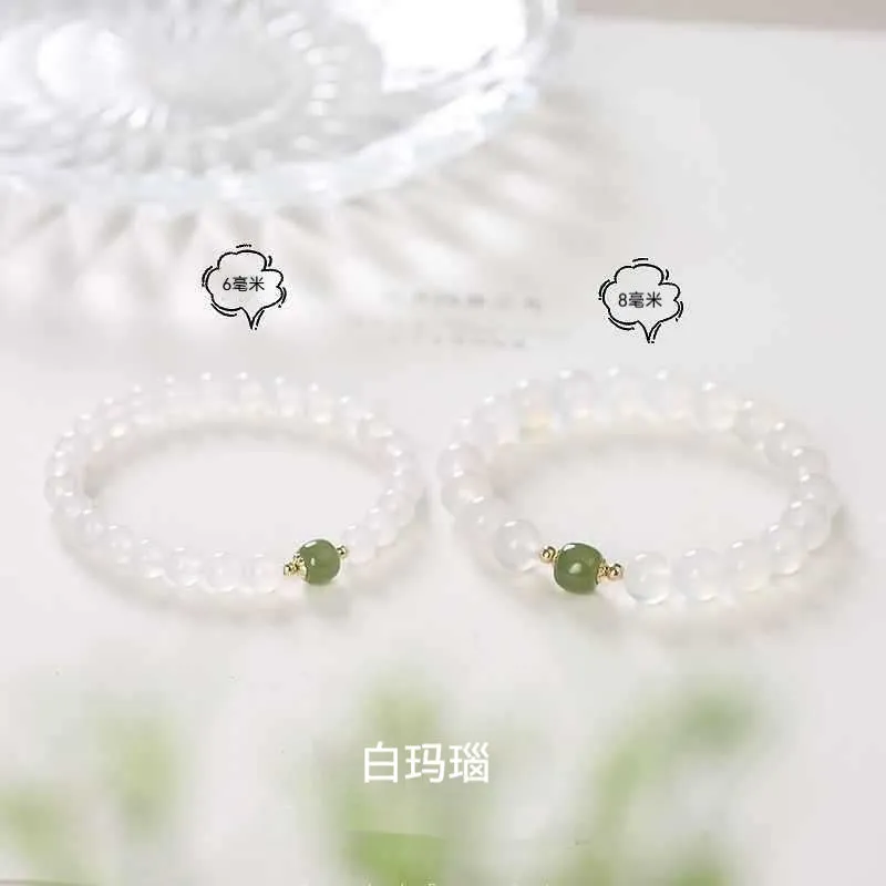 Handmade natural white agate and Hetian jade crystal bracelet with cinnabar inlay on a wrist.
