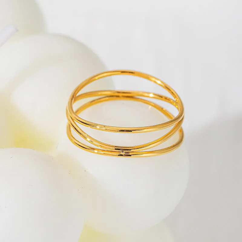 Gold geometric coil ring on a plain background, showing its three-layer titanium steel construction