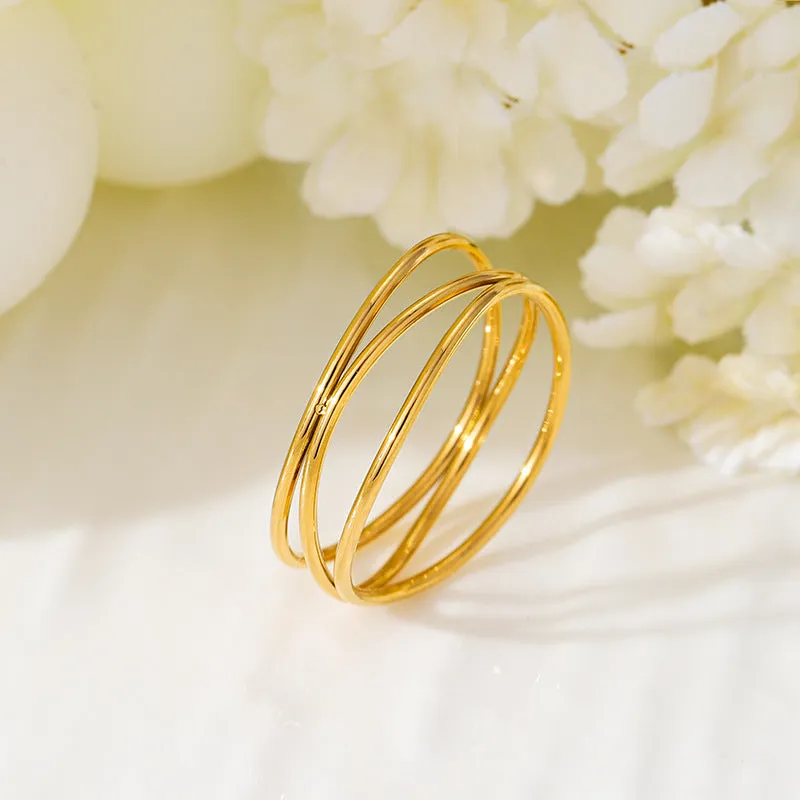 Gold geometric coil ring on a plain background, showing its three-layer titanium steel construction