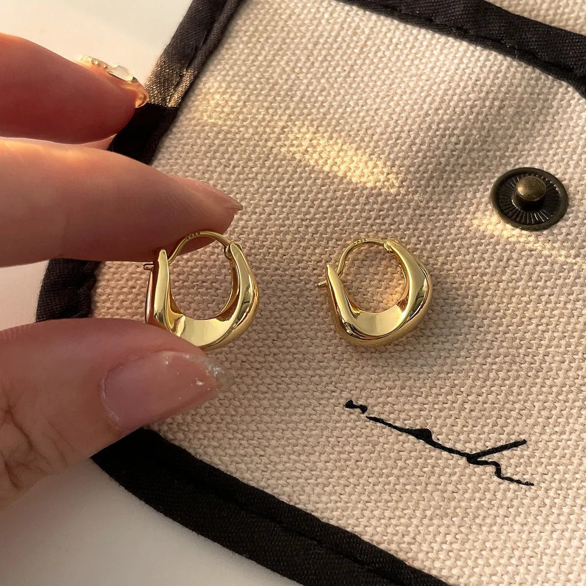 Gold pair of irregular geometric earrings with 925 silver needle posts on white background