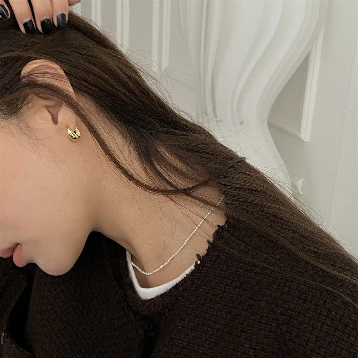 Gold pair of irregular geometric earrings with 925 silver needle posts on white background