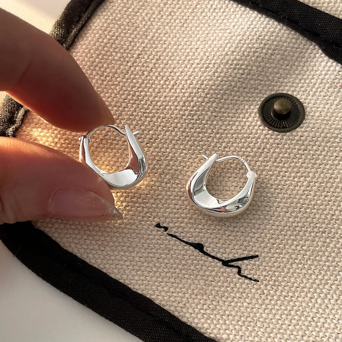 Gold pair of irregular geometric earrings with 925 silver needle posts on white background