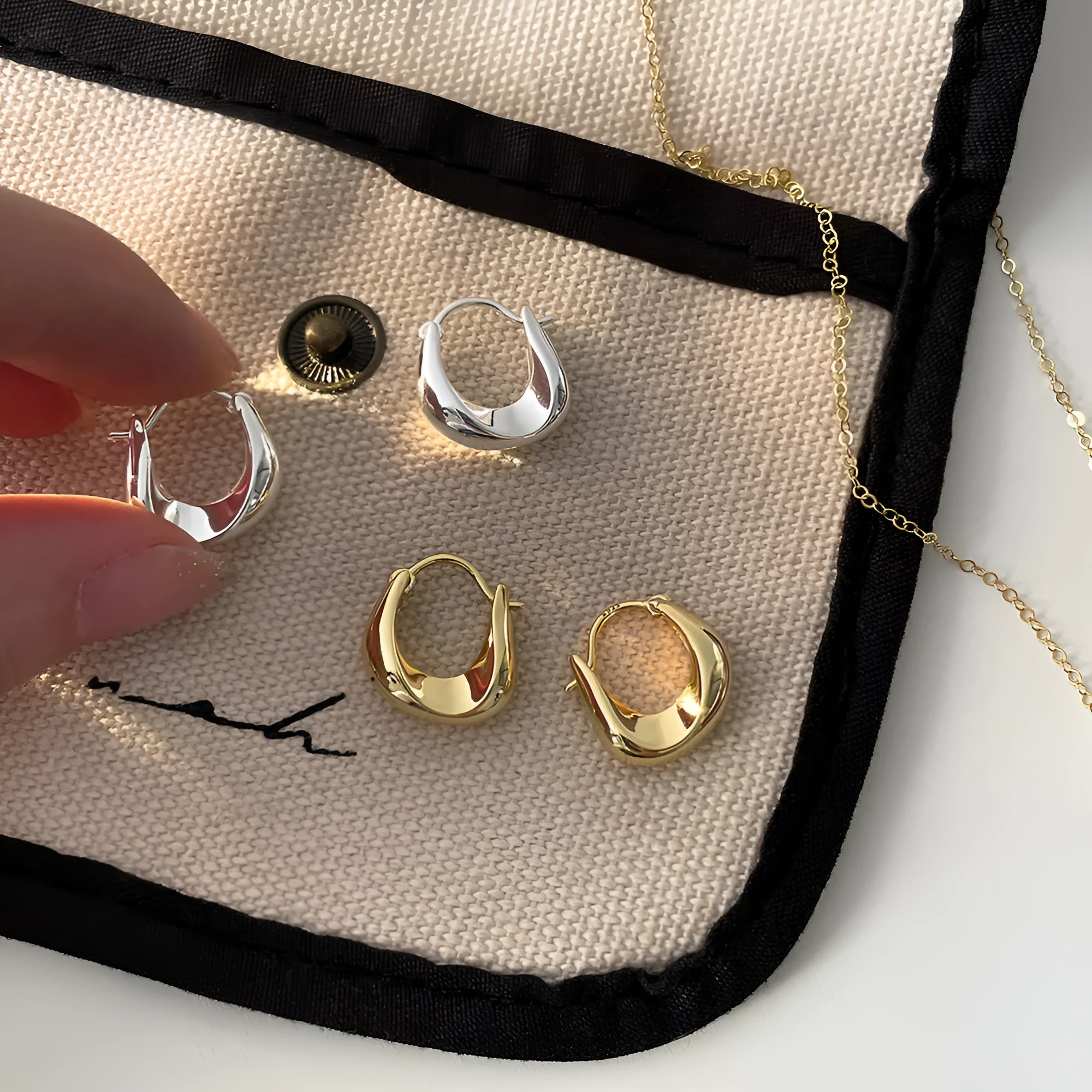 Gold pair of irregular geometric earrings with 925 silver needle posts on white background