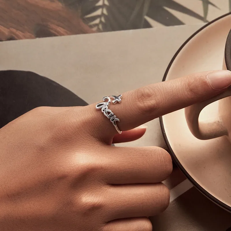 S925 sterling silver cross letter open ring with oxidised finish and adjustable opening on neutral background