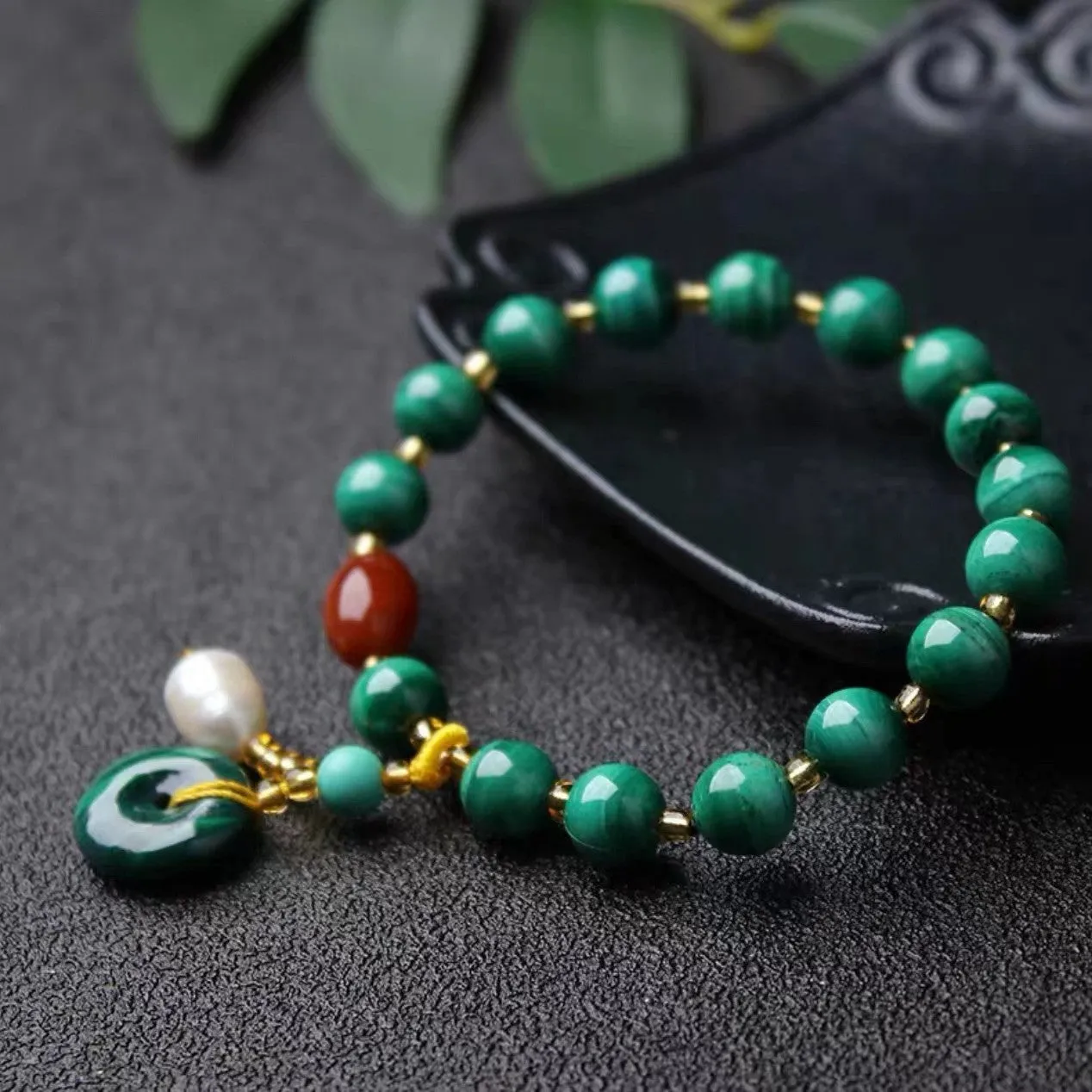 Handmade natural malachite and red agate bracelet with 7-8mm barrel beads on a wrist.
