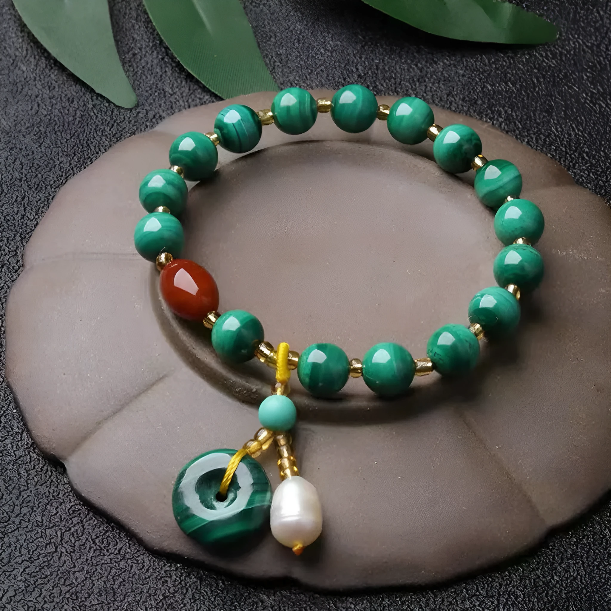 Handmade natural malachite and red agate bracelet with 7-8mm barrel beads on a wrist.