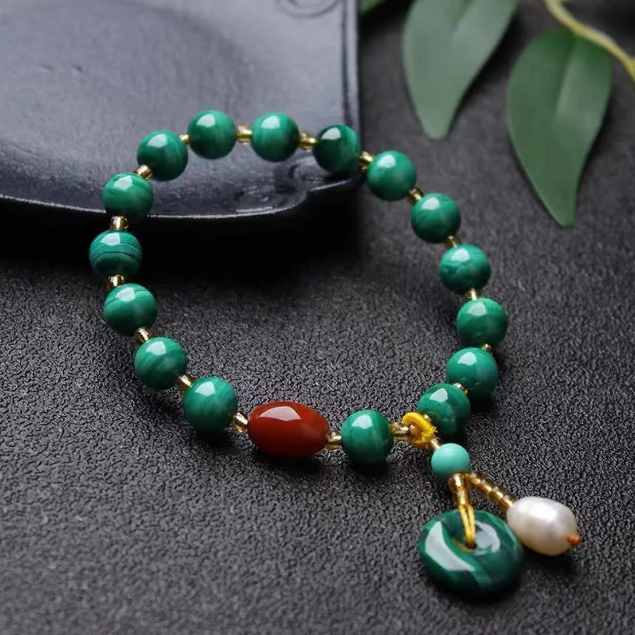 Handmade natural malachite and red agate bracelet with 7-8mm barrel beads on a wrist.