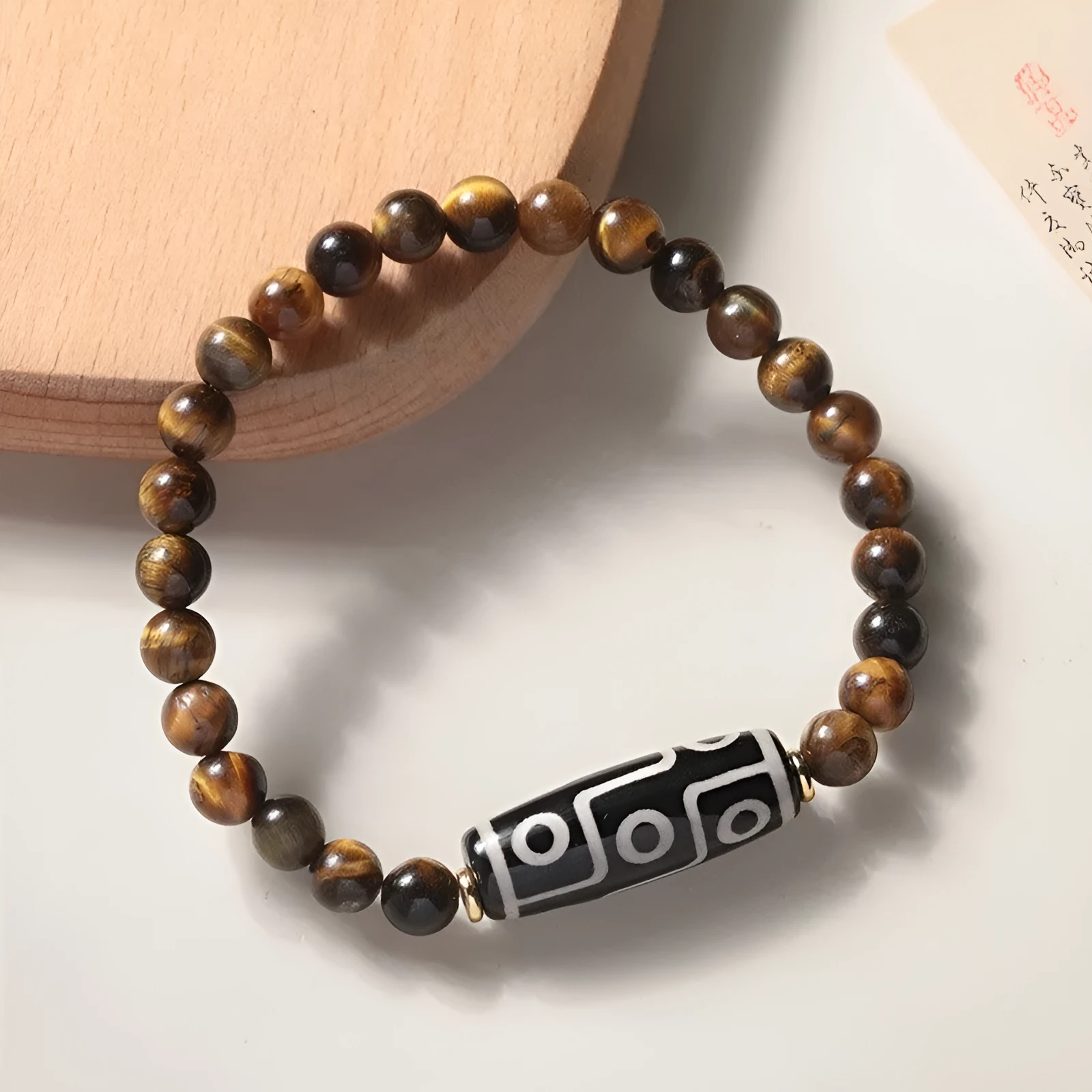 Tigereye Dzi bead single circle Buddha rosary bracelet on a wrist.