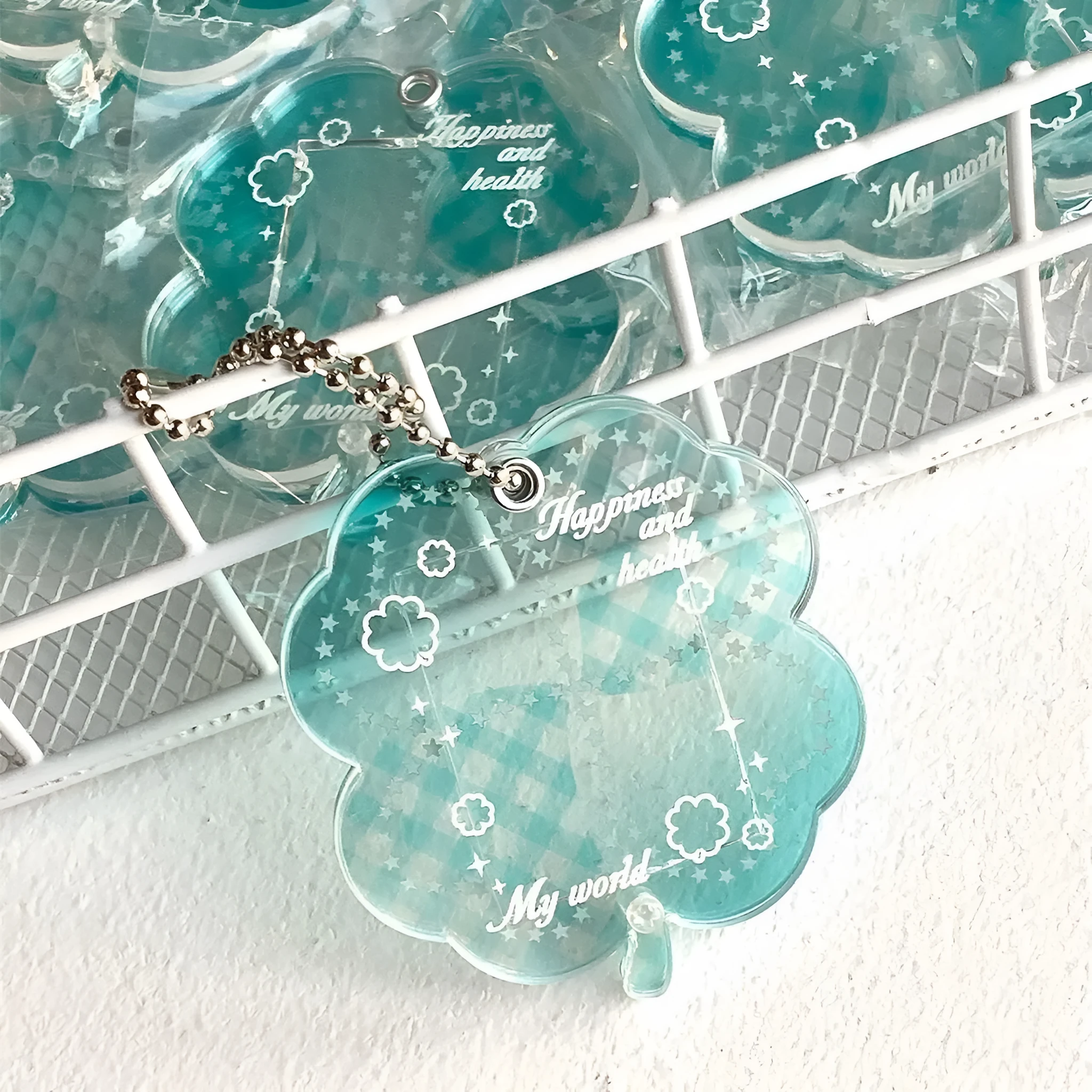 Acrylic four-leaf clover pendant keychain for phones in blue, green, and mint colour options.