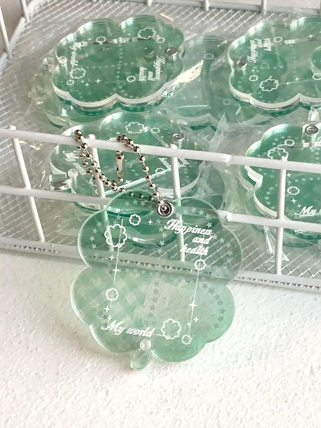 Acrylic four-leaf clover pendant keychain for phones in blue, green, and mint colour options.