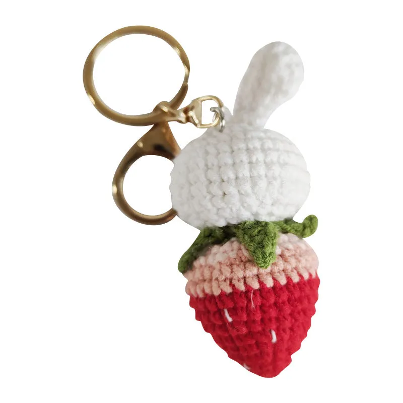 Close-up of a white hand-woven wire rabbit keychain pendant with a strawberry pattern detail.