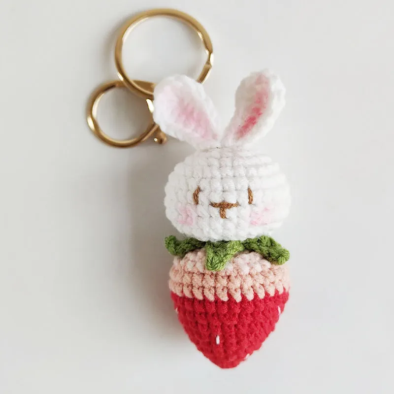 Close-up of a white hand-woven wire rabbit keychain pendant with a strawberry pattern detail.