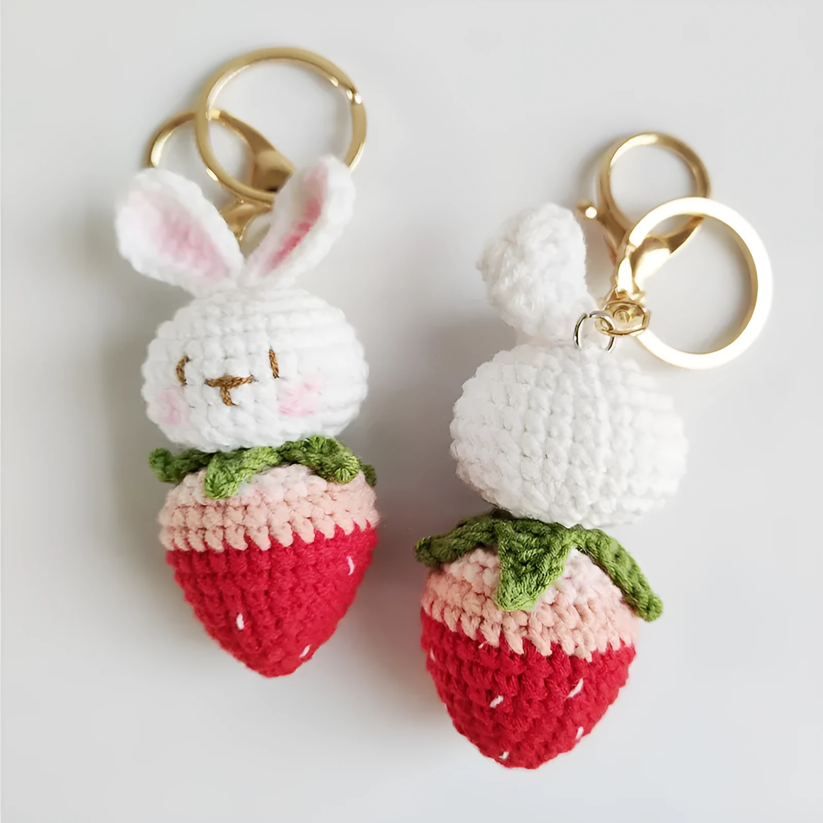 Close-up of a white hand-woven wire rabbit keychain pendant with a strawberry pattern detail.