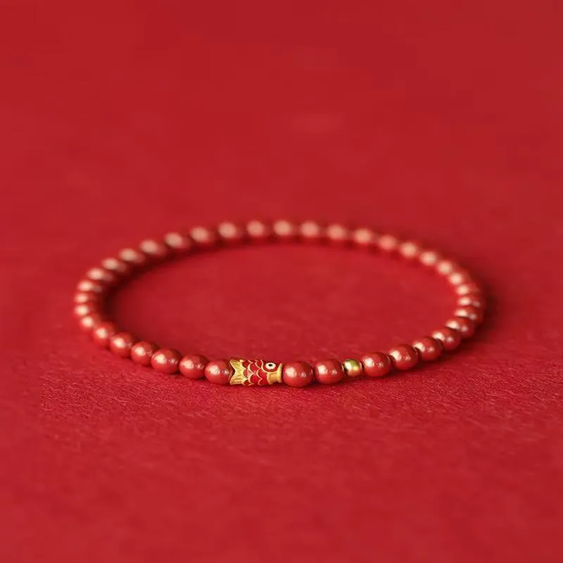 Handmade natural cinnabar koi bracelet with gold balls on a bead, showing traditional Chinese style.