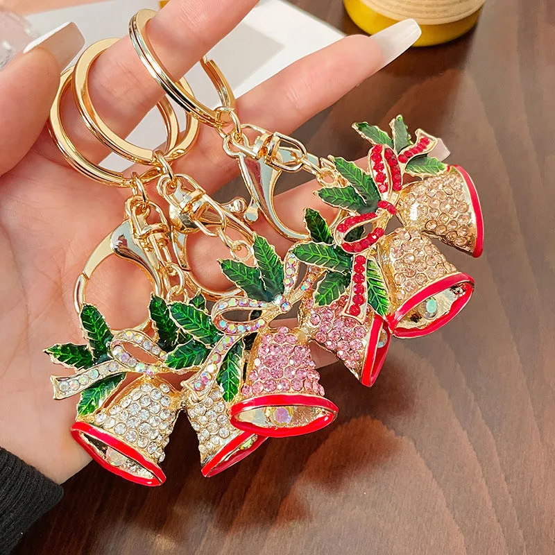 Christmas bell shaped metal keychain with diamond studded surface in champagne colour on white background