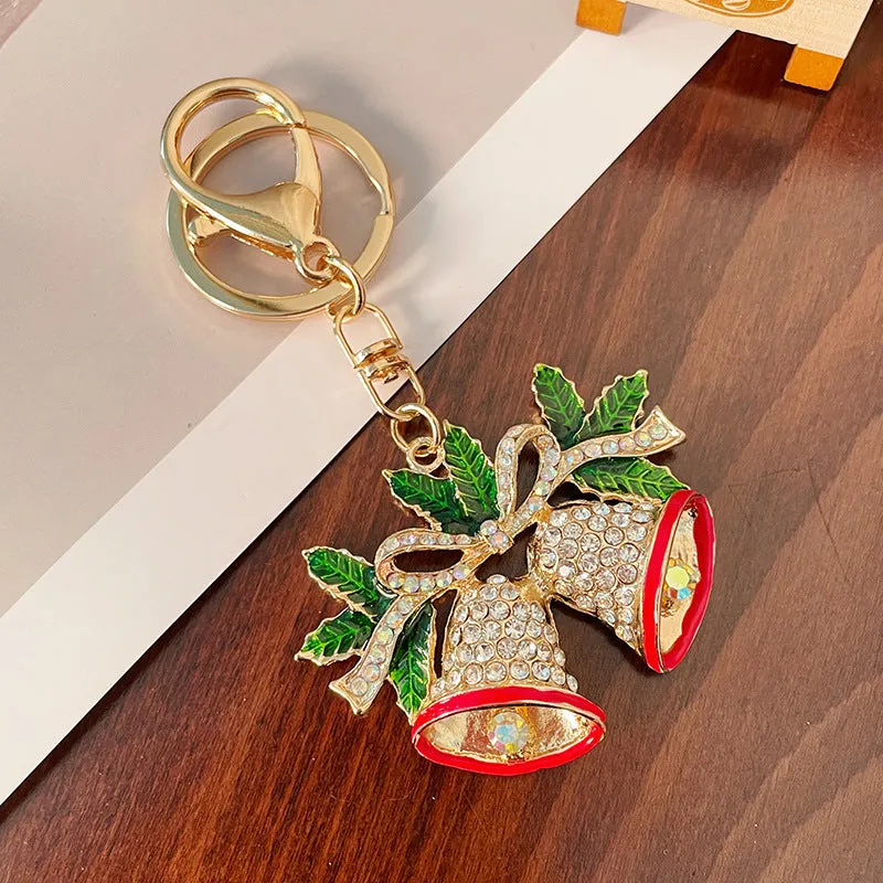 Christmas bell shaped metal keychain with diamond studded surface in champagne colour on white background