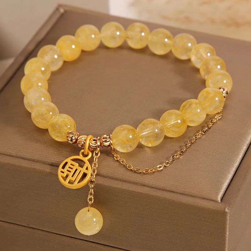 Natural citrine stone bracelet with Chinese character charm and dangling tassel.