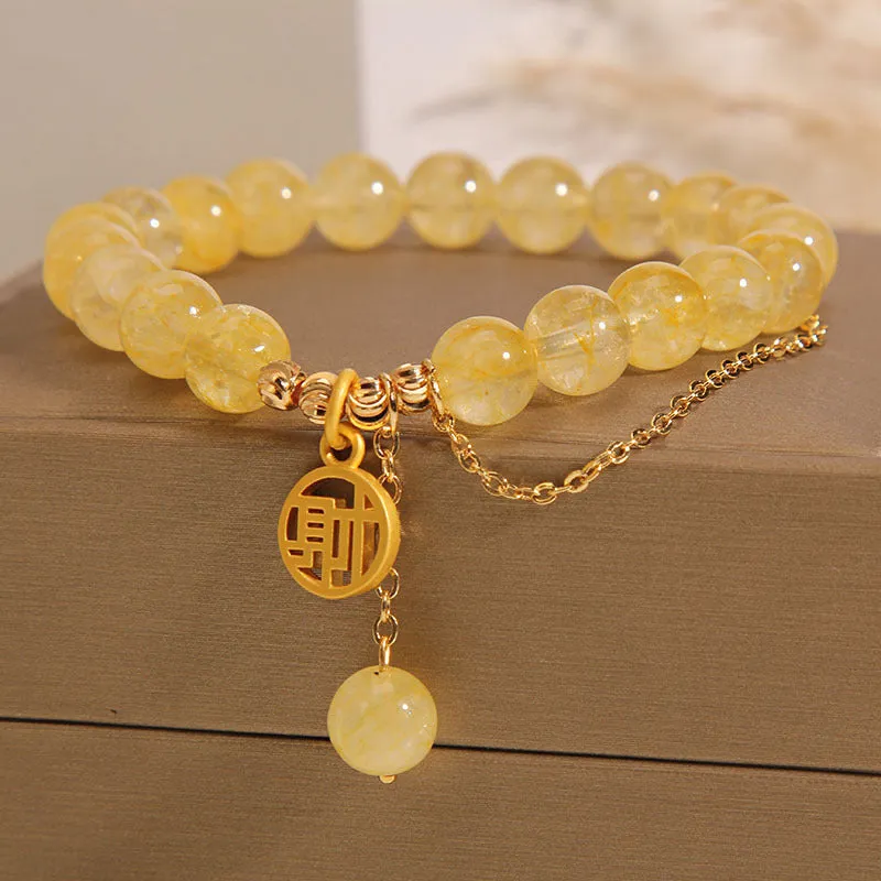 Natural citrine stone bracelet with Chinese character charm and dangling tassel.