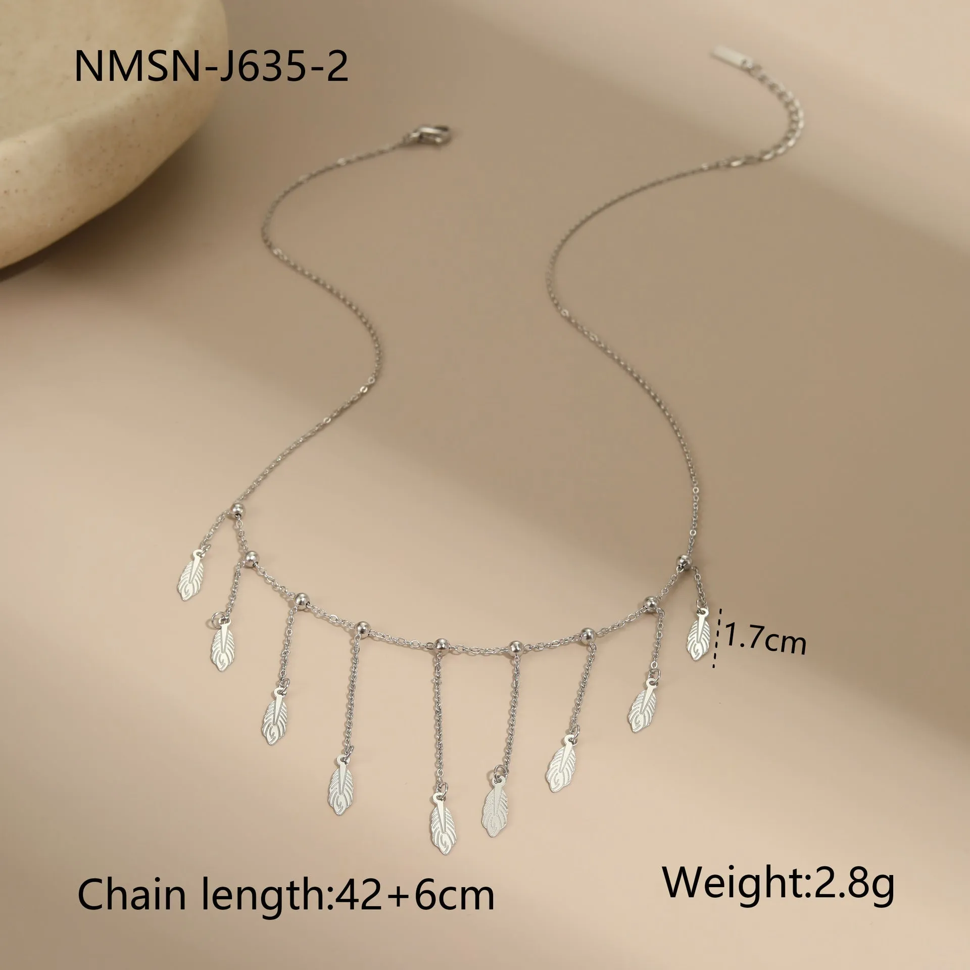 Gold clavicle chain necklace with geometric pendant and tassel detail on a woman's neckline