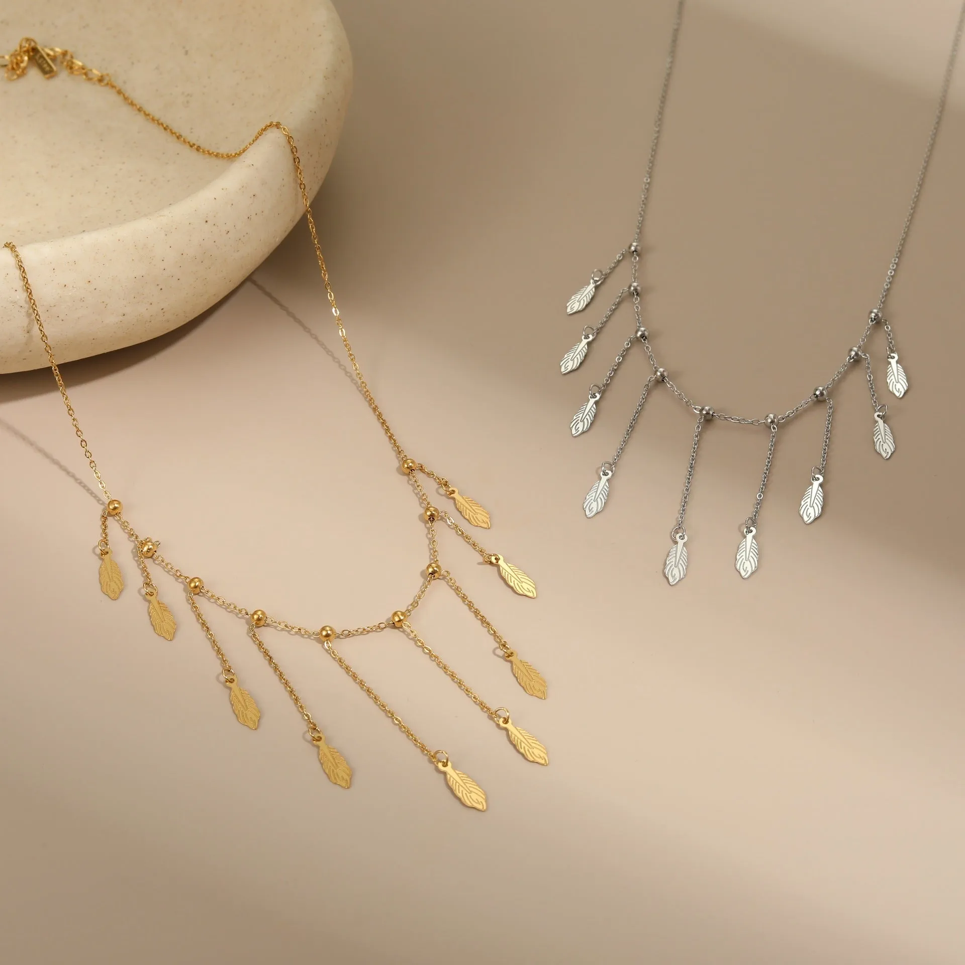 Gold clavicle chain necklace with geometric pendant and tassel detail on a woman's neckline