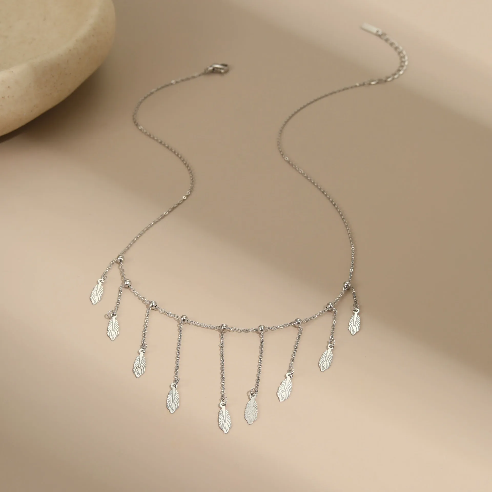 Gold clavicle chain necklace with geometric pendant and tassel detail on a woman's neckline