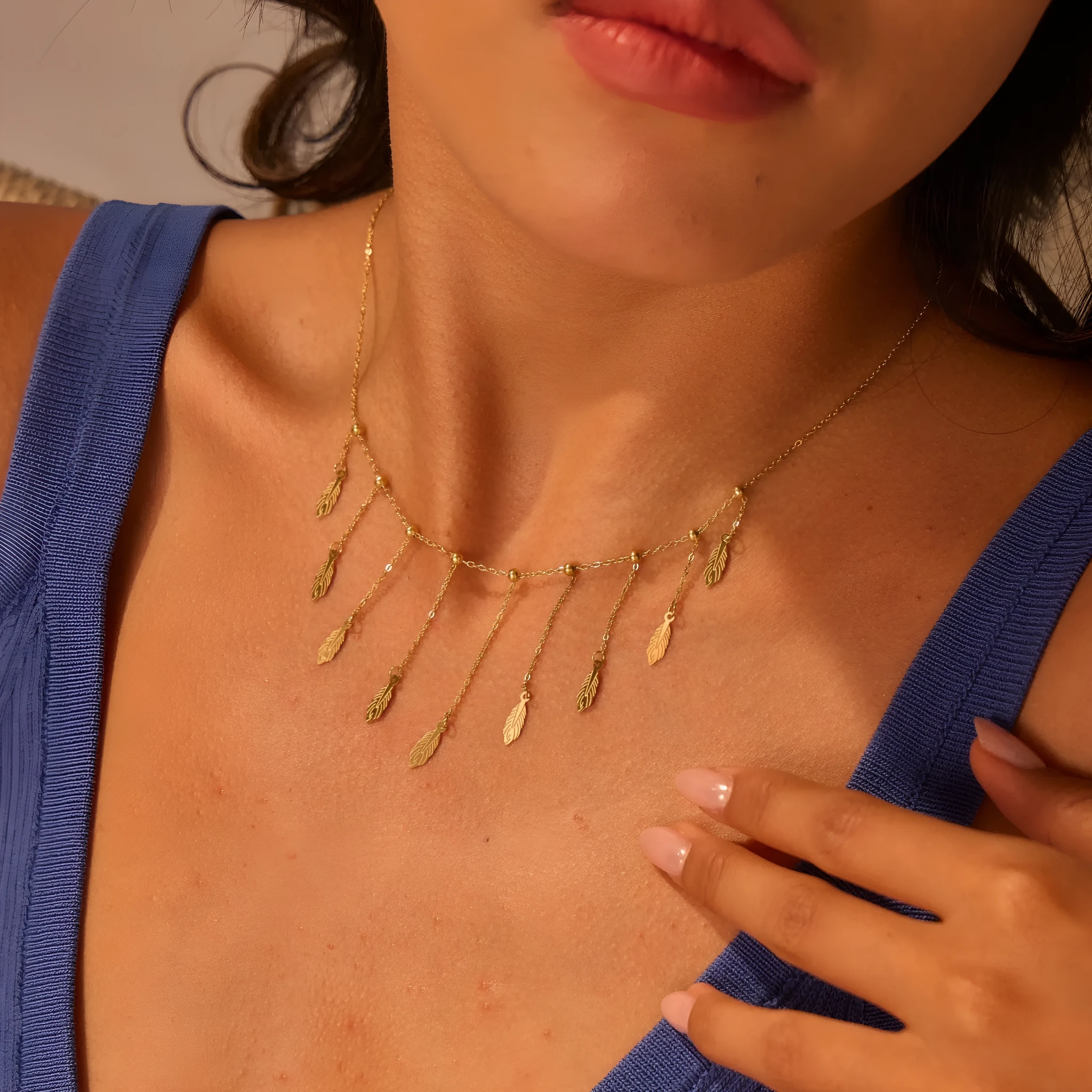 Gold clavicle chain necklace with geometric pendant and tassel detail on a woman's neckline