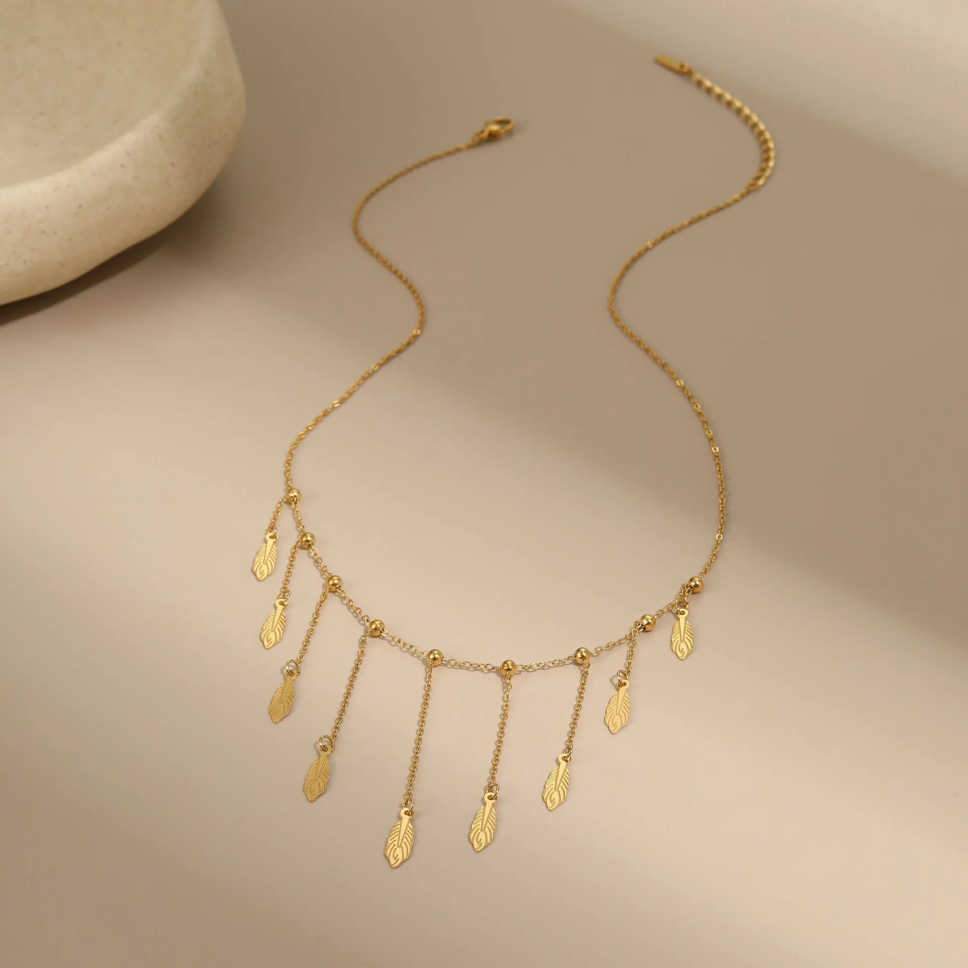 Gold clavicle chain necklace with geometric pendant and tassel detail on a woman's neckline