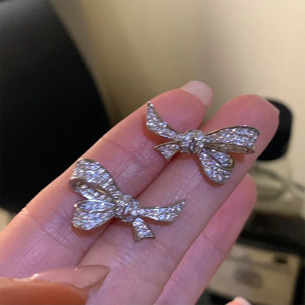 Gold electroplated bowknot ear studs with miniature zircon inlay and 925 silver needle on white background