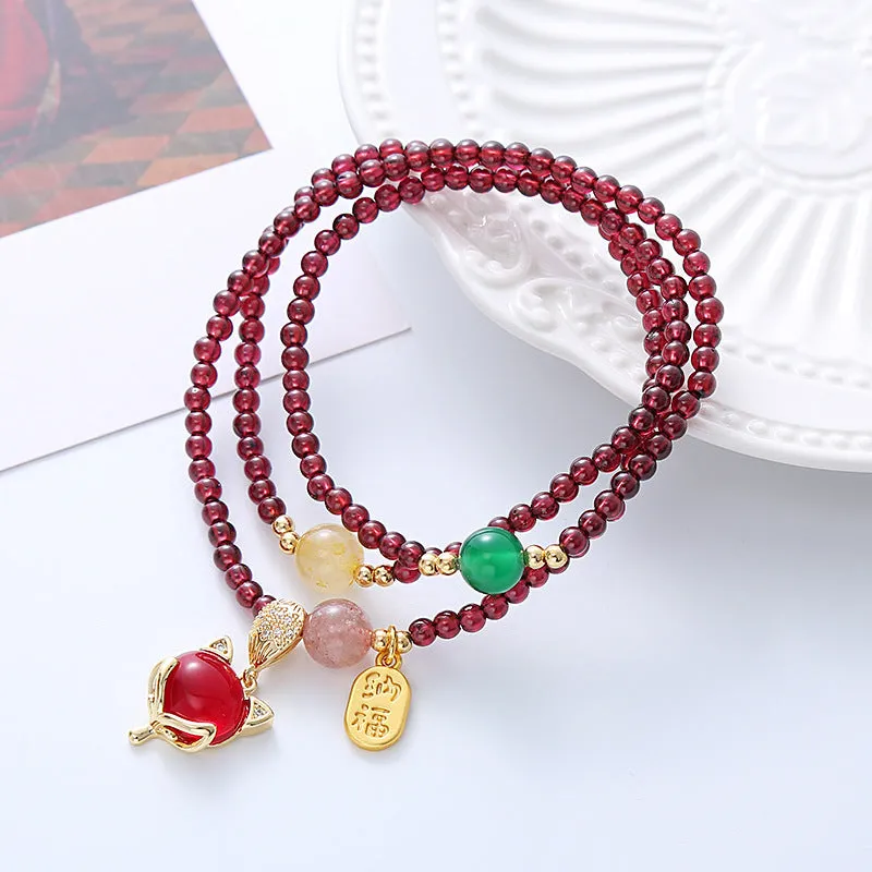 Purplish red adjustable rope bracelet with a detailed natural garnet fox charm.